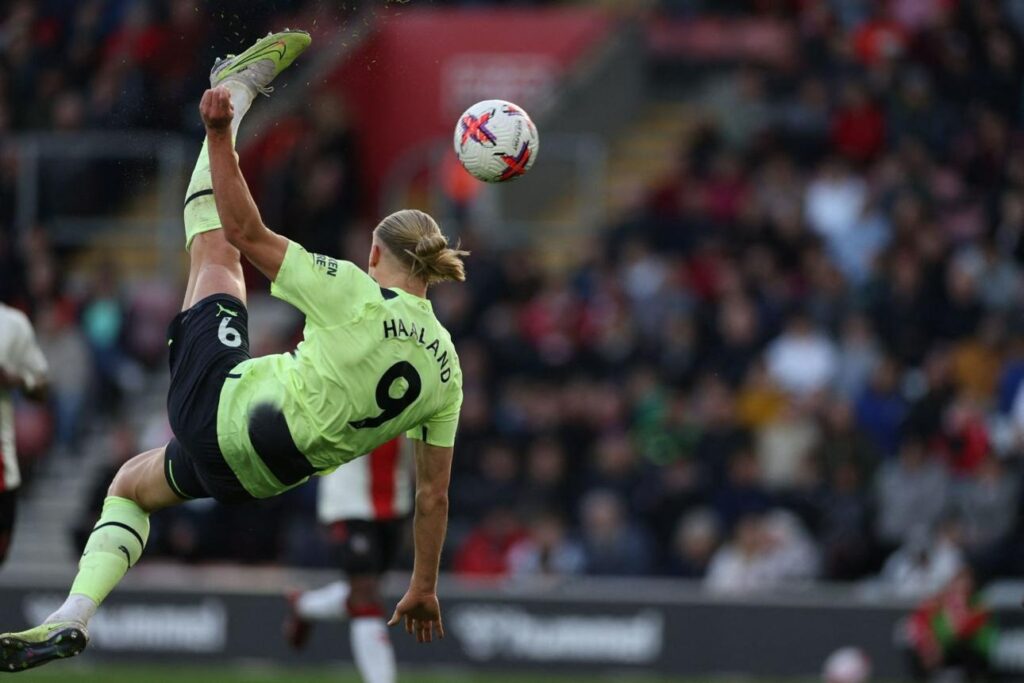 Erling Haaland attempting an acrobatic bicycle kick for Manchester City during a football match