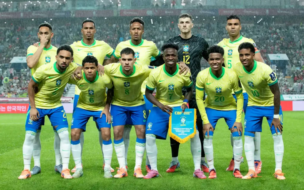 Brazil national football team players in yellow and blue kits posing together on the pitch before a match.
